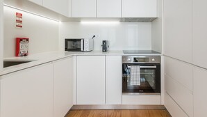 A modern kitchen with white cabinets, a microwave, a coffee maker, and an oven. - Sunny getaway in Rua do Bonjardim (Porto)