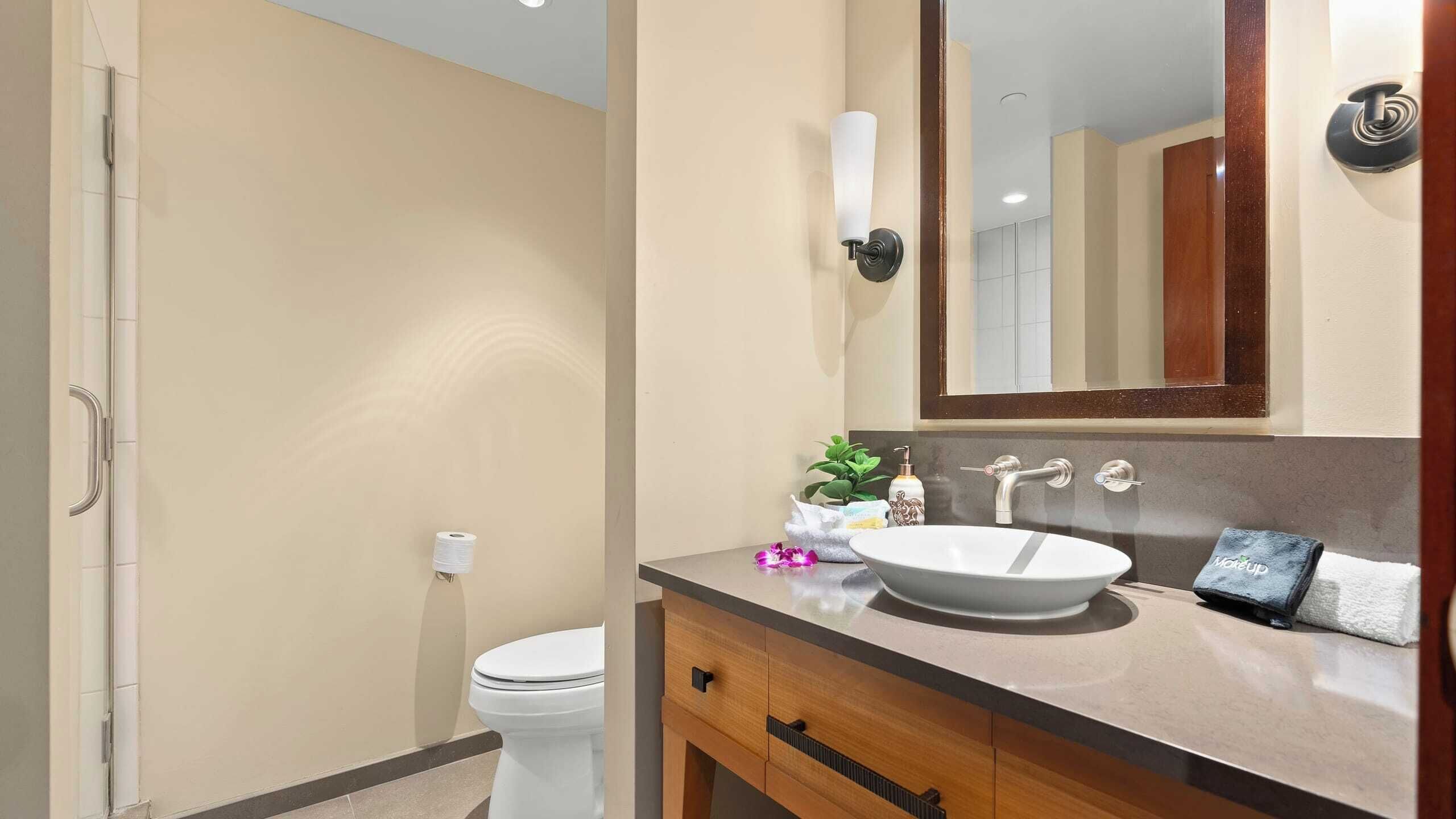 Une salle de bain comprenant des toilettes, un lavabo, un miroir et une douche.