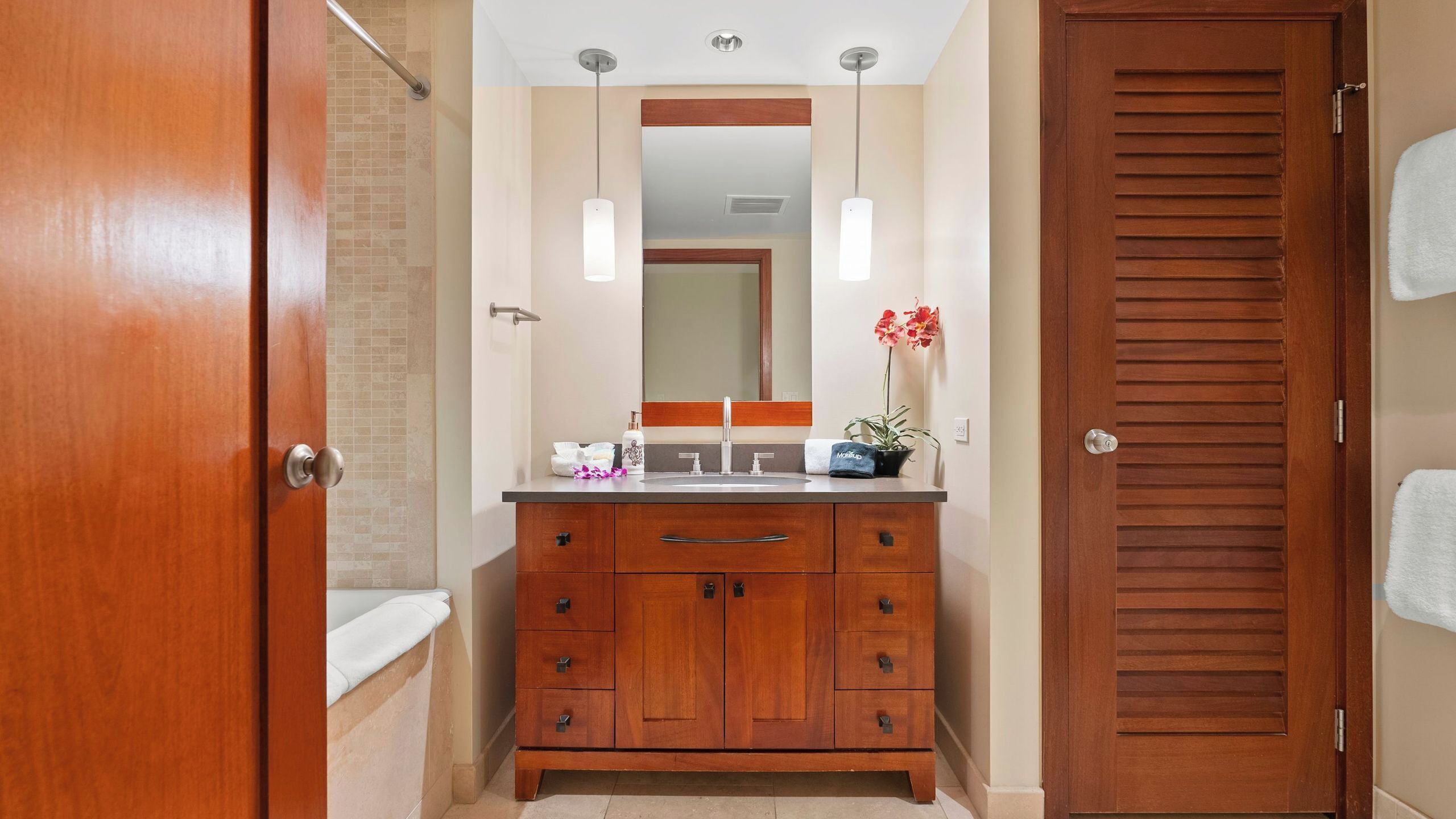 Une salle de bain avec un meuble-lavabo en bois, un miroir, un lavabo et un porte-serviettes.