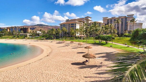 Ein Strandresort mit mehreren Hotelgebäuden, einem Sandstrand und Palmen.