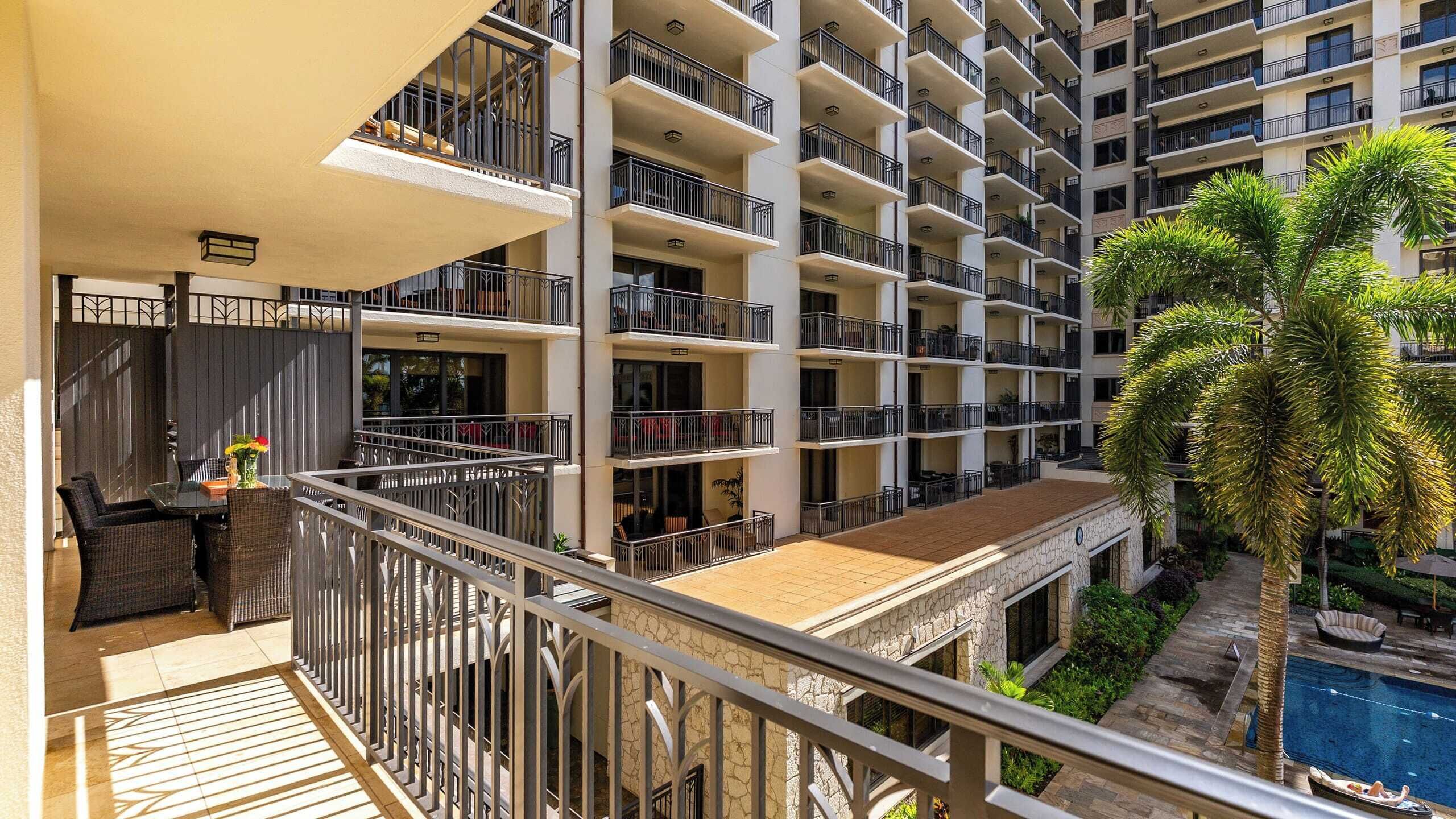 A multi-story hotel with balconies, a pool, and outdoor seating.