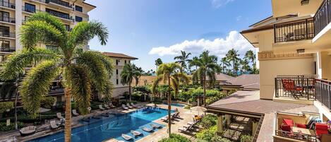A hotel with a swimming pool, palm trees, and a view of the ocean.