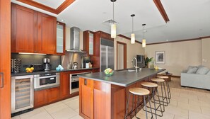 A modern kitchen with wooden cabinets, stainless steel appliances, and a central island with bar stools.