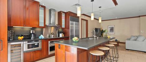 A modern kitchen with wooden cabinets, stainless steel appliances, and a central island with stools.