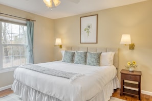 A bedroom with a large bed, two bedside lamps, a framed floral artwork, and a nightstand with a vase of flowers. - Penny by Avantstay Weaverville Home w/ Mtn Views (Weaverville)