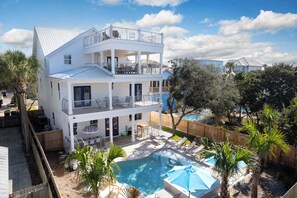 A two-story house with a balcony, a swimming pool, and a fenced yard.