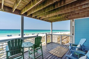 Une terrasse en bois avec des chaises donnant sur une plage.