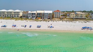 Un hotel frente a la playa con varias edificaciones, una playa de arena y aguas turquesas cristalinas.