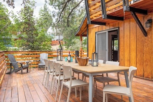 A wooden deck with a table and chairs, a wooden fence, and a building with a door.