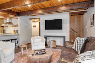 A cozy living room with a fireplace, a television mounted on the wall, and a leather sofa.