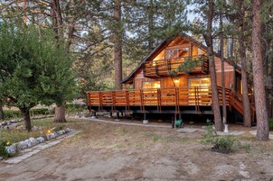 A wooden cabin with a balcony, surrounded by trees.