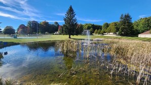 A clear pond with a fountain, surrounded by trees and a grassy area. - Gorgeous 4 bedroom condo - 10 minutes from Harbor Springs & Ski Resorts (Harbor Springs)