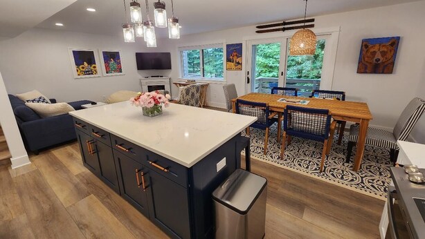 A modern kitchen with a central island, dining area with a wooden table and chairs, and a sofa in the living area. - Gorgeous 4 bedroom condo - 10 minutes from Harbor Springs & Ski Resorts (Harbor Springs)
