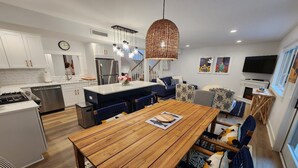 A modern kitchen with white cabinets, a wooden dining table, and a hanging light fixture. - Gorgeous 4 bedroom condo - 10 minutes from Harbor Springs & Ski Resorts (Harbor Springs)