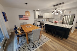 Uma cozinha moderna com armários brancos, eletrodomésticos de aço inoxidável e uma mesa de jantar de madeira.