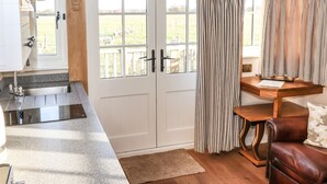 Ein Zimmer mit Küchenzeile, einem Holzesstisch, einer Ledersofa und einem großen Fenster mit Vorhängen.