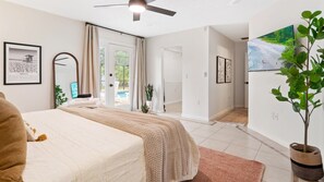 Relax in this serene bedroom with a large bed, ceiling fan, and pool view through the glass door.