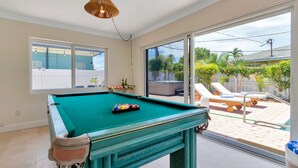A pool table in a room with large windows and a view of a pool outside. - Summerfin by Avantstay Sunny Retreat Minutes From the Shore! (Pompano Beach)