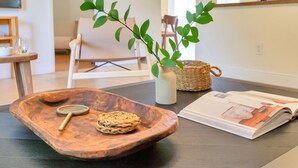 A wooden tray with a woven item and a magnifying glass on a table, a woven basket, a vase with green leaves, and an open magazine. - Summerfin by Avantstay Sunny Retreat Minutes From the Shore! (Pompano Beach)