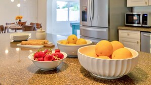 A kitchen with a granite countertop, a bowl of strawberries, and a bowl of oranges. - Summerfin by Avantstay Sunny Retreat Minutes From the Shore! (Pompano Beach)