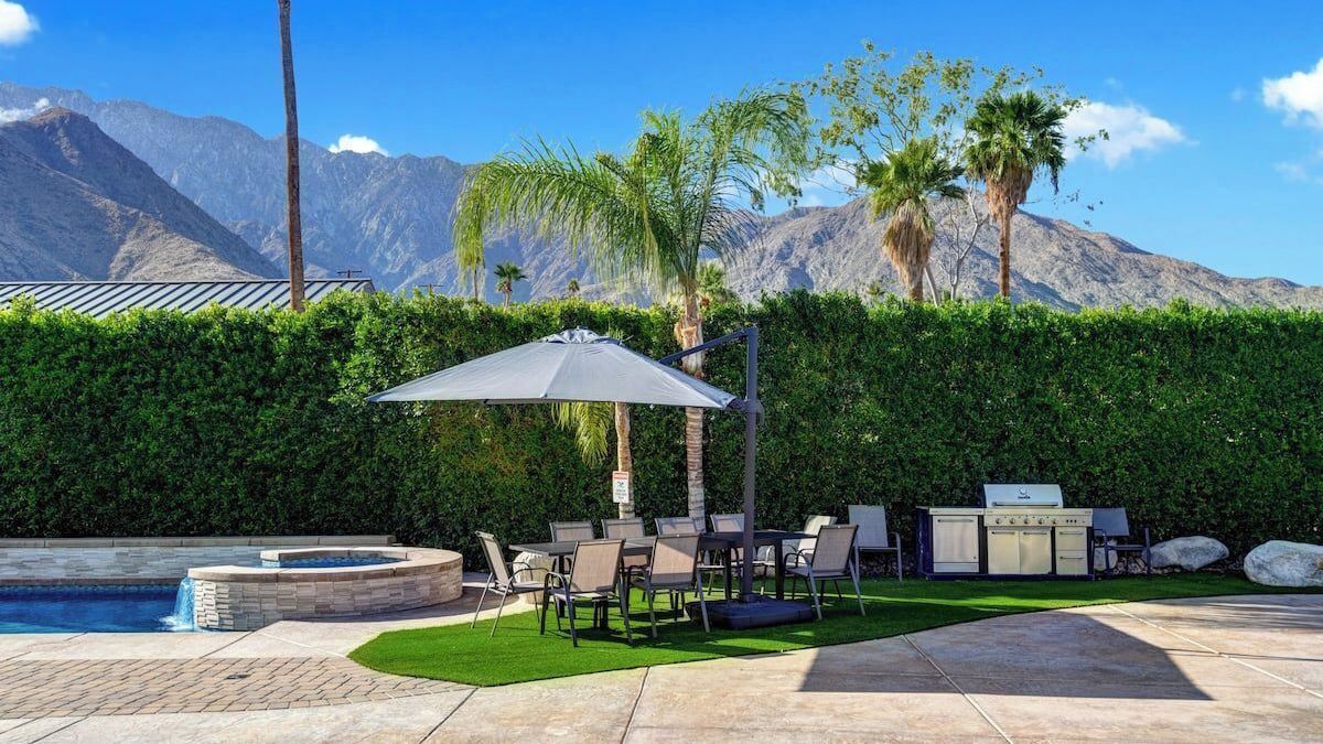Zona junto a la piscina con jacuzzi, mobiliario exterior y una parrilla.