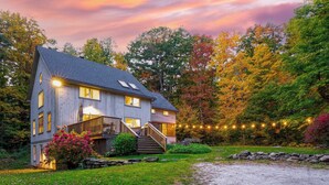 A two-story house with a porch, a stone wall, and a gravel driveway. - Woodfall by Avantstay Tons of Outdoor Space (Monterey)
