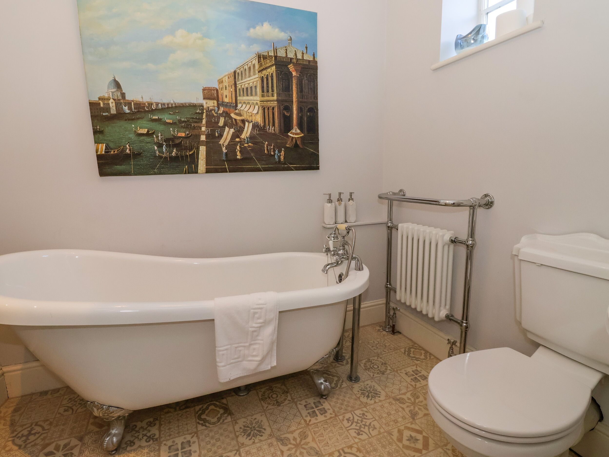 A bathroom with a freestanding bathtub, a toilet, and a radiator.