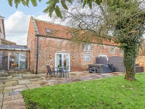 A brick building with a tiled roof, a patio with a table and chairs, and a large tree in the foreground. - Servant's Quarters (York)