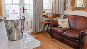 A room with a leather sofa, a small wooden table, a metal bucket with glasses, and a window with curtains. - The Studio (York)
