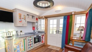 A compact kitchen with a built-in oven, a sink, and a flat-screen TV. - The Studio (York)
