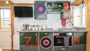 A modern kitchen with a built-in oven, a sink, and a television mounted above the counter.
