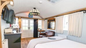 A bedroom with a bed, a desk, a chair, a television, and a window with curtains.