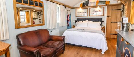 A cozy room with a bed, a leather sofa, a wooden table, and a ceiling mural.