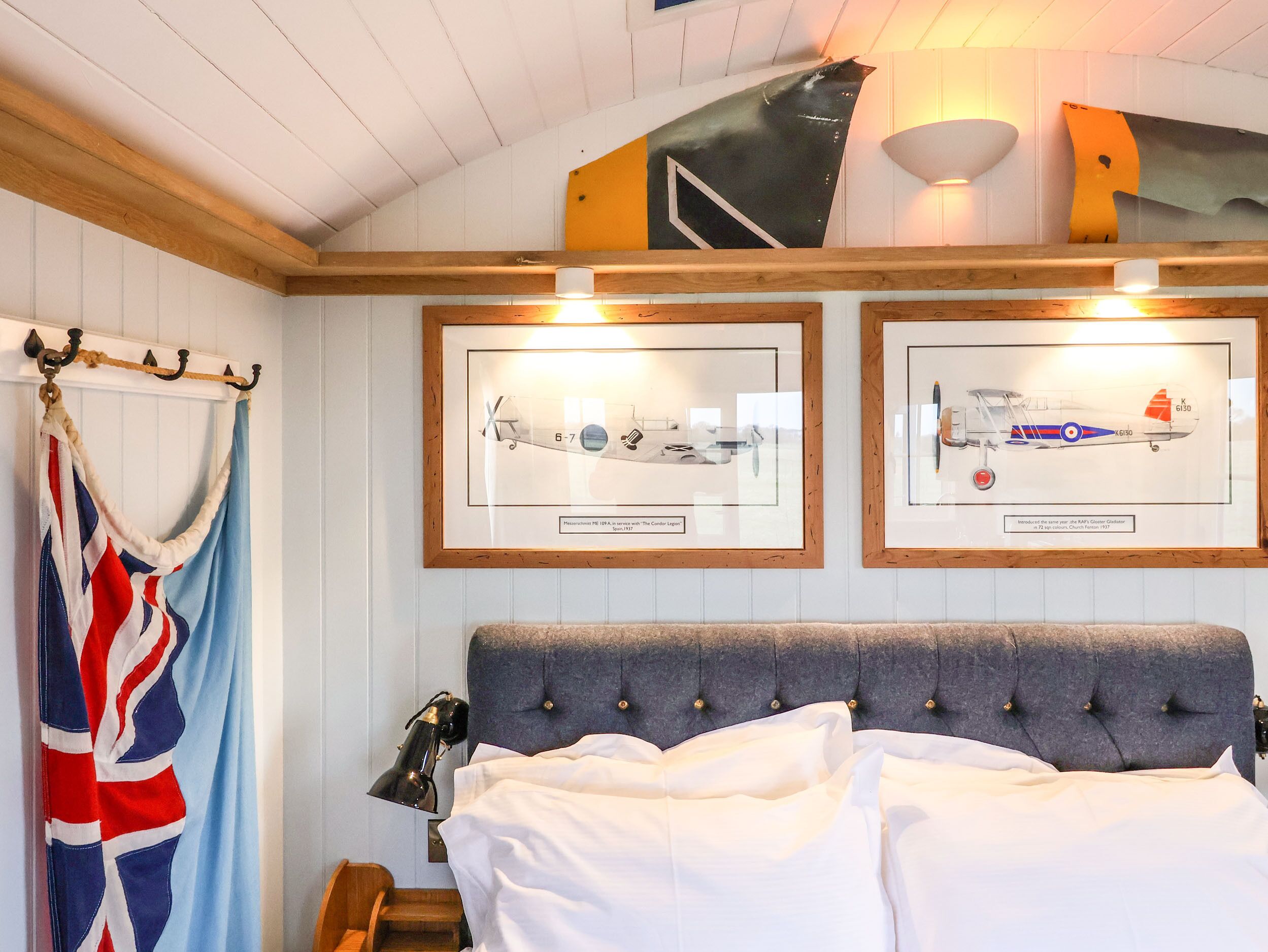 A bedroom with a bed, a framed picture of an airplane, and a window with curtains.