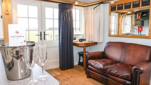A room with a leather sofa, a bar area with a champagne bucket and glasses, and a mirror with menu items.