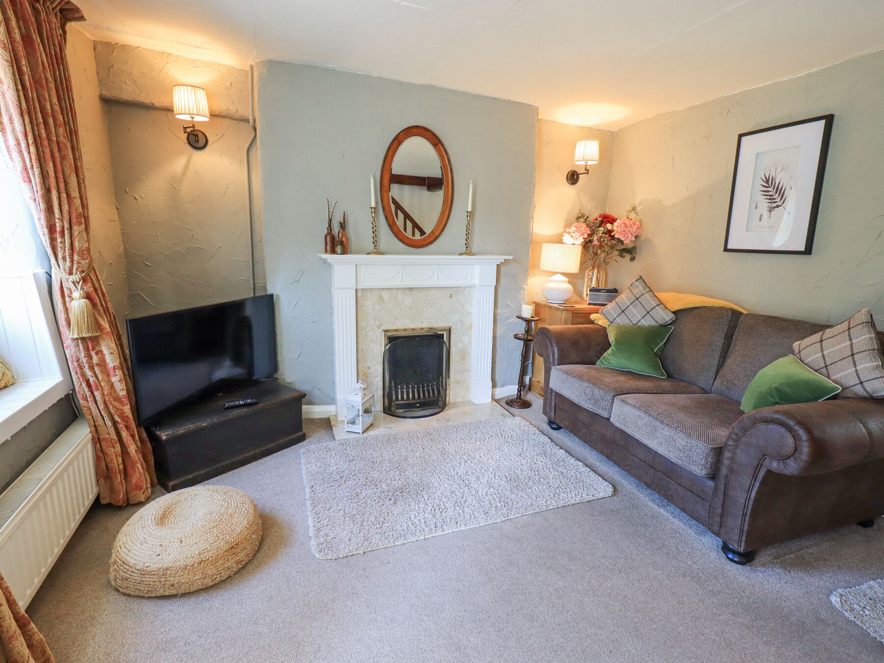 A living room with a fireplace, a sofa, a television, and a decorative mirror.