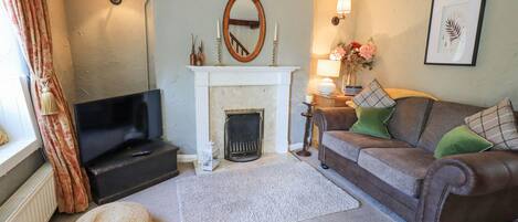 A living room with a fireplace, a sofa, a television, and a decorative mirror.