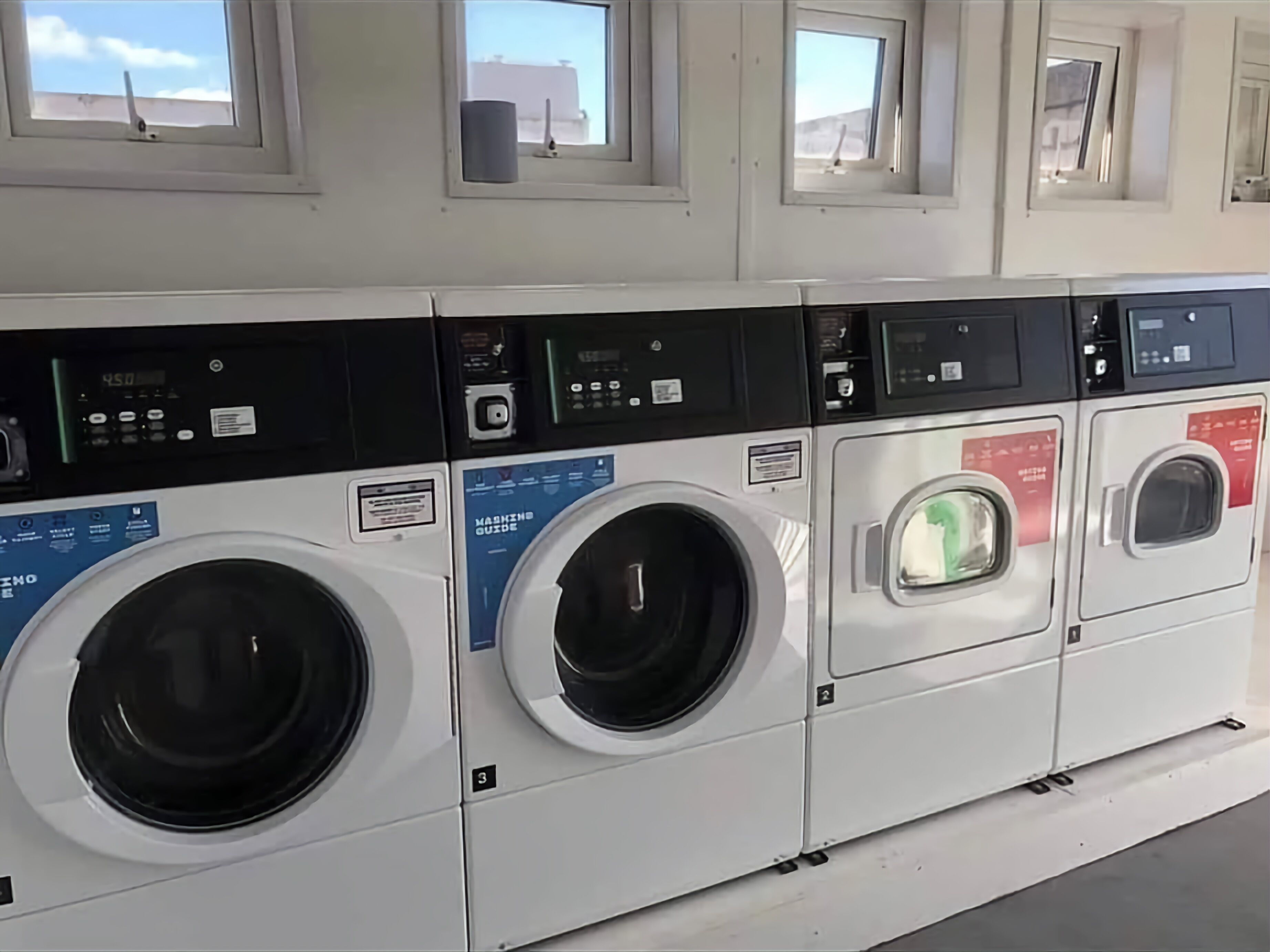 A row of front-loading washing machines in a commercial setting.