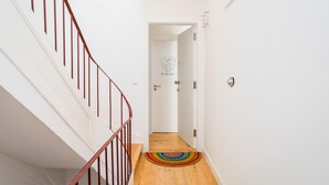 Una escalera con barandilla y piso de madera que conduce a una puerta con un logotipo en forma de corazón.
