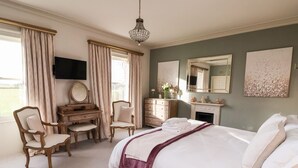 A bedroom with a large bed, a desk with a chair, a dresser, and a fireplace. - The Stables and West Wing (York)