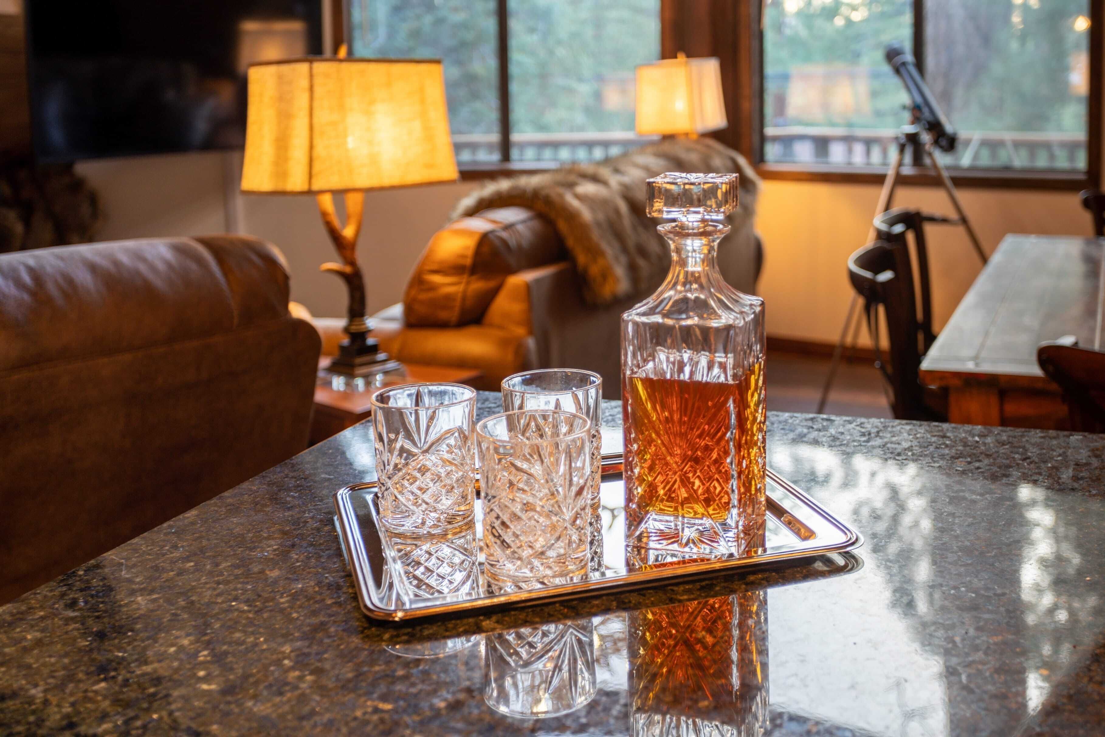 Un plateau avec une carafe et trois verres, posé sur un comptoir en granit.