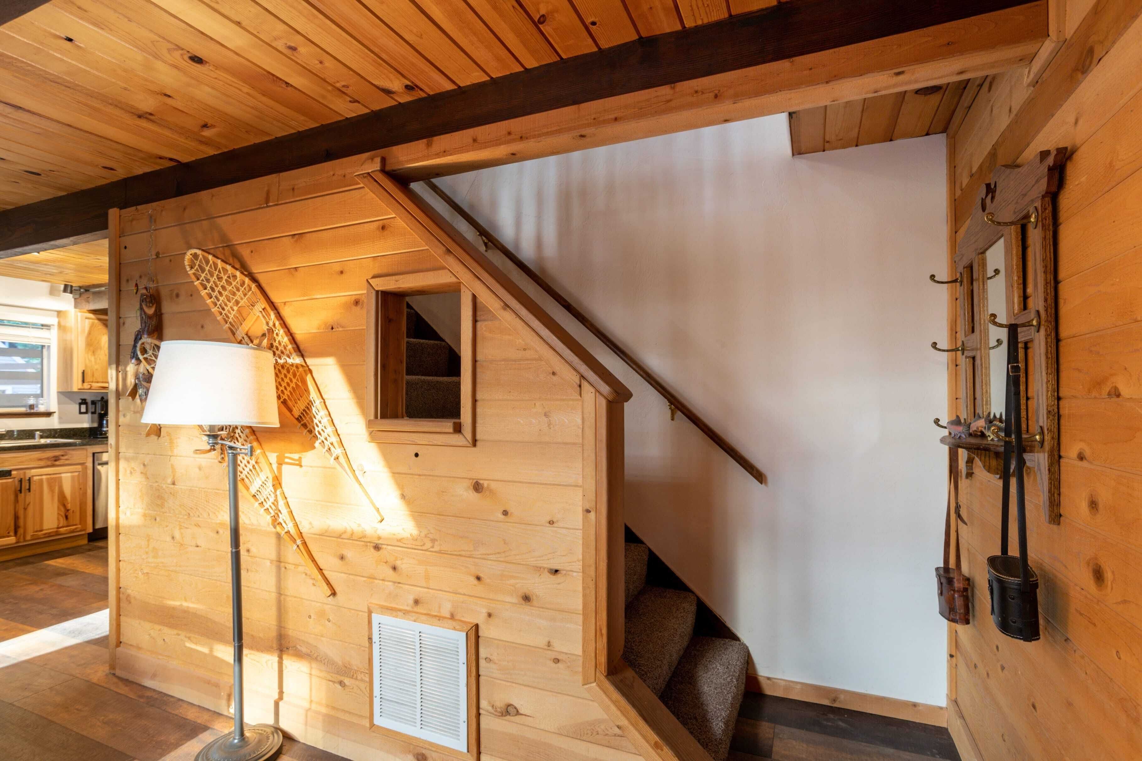 A wooden interior with a staircase, a lamp, and a wall-mounted coat rack.