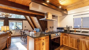 Une cuisine avec des meubles de rangement en bois, une cuisinière et une grande fenêtre.