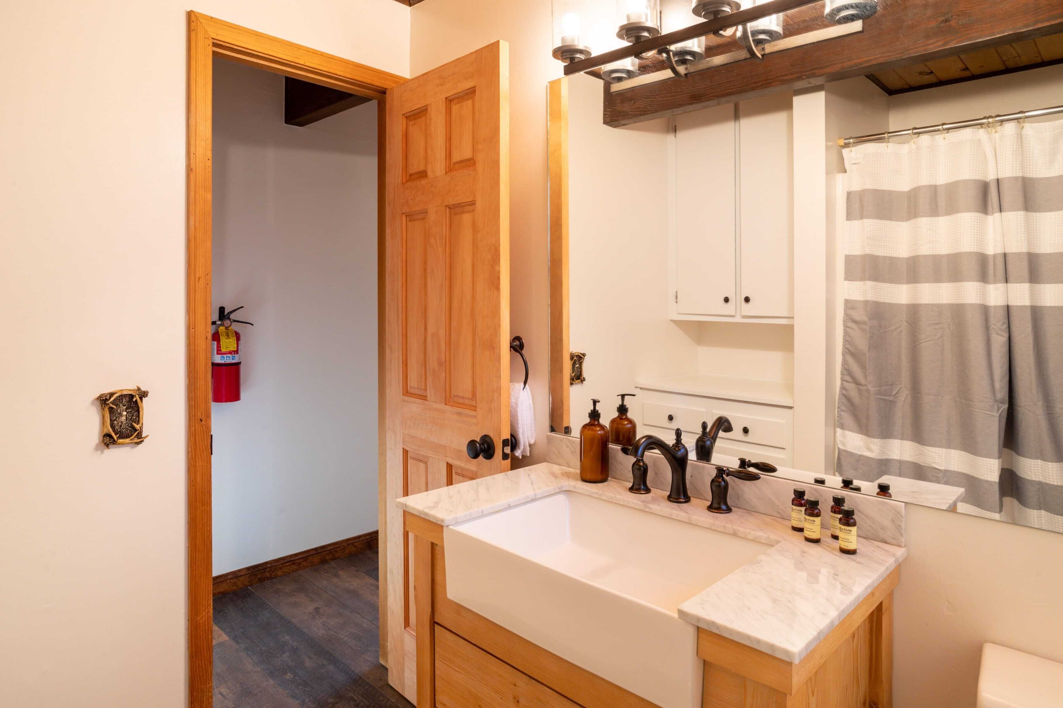 A bathroom with a double sink, wooden cabinets, a mirror, and a shower curtain.