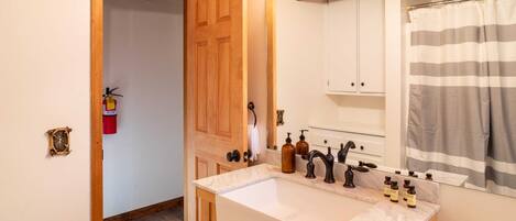 A bathroom with a double sink, wooden cabinets, a mirror, and a shower curtain.