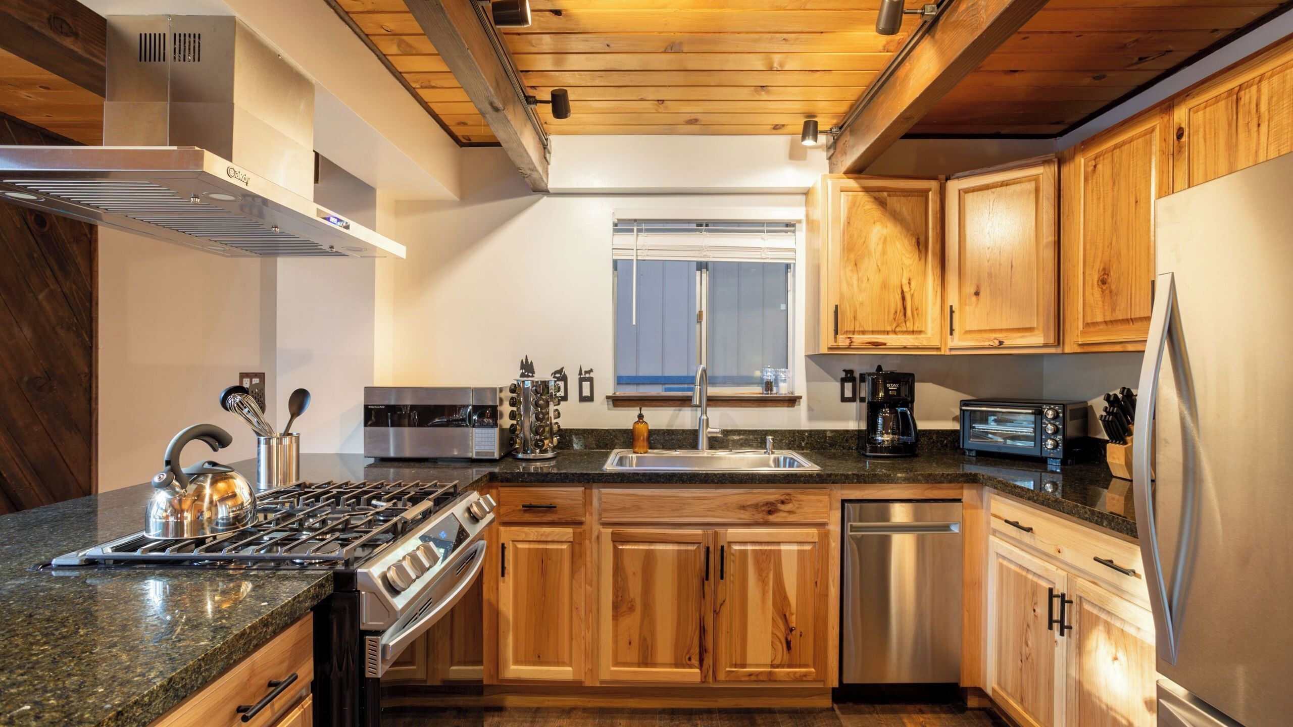 A modern kitchen with wooden cabinets, a stainless steel stove, and a dishwasher.