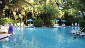 A swimming pool surrounded by palm trees and lounge chairs.