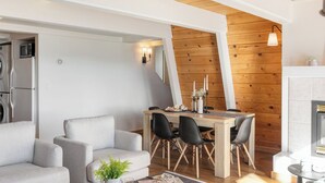 A modern living room with a dining area, grey sofas, a wooden dining table, and a fireplace. - Chickaree & Chickadee Buyout by Avantstay 2 Sister Cabins (Tahoe City)