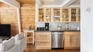 A modern kitchen with wooden cabinets, a stainless steel dishwasher, and a coffee station. - Chickaree & Chickadee Buyout by Avantstay 2 Sister Cabins (Tahoe City)