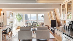 A modern loft apartment with a dining area, seating, kitchen, and large windows offering city views. - Chickaree & Chickadee Buyout by Avantstay 2 Sister Cabins (Tahoe City)